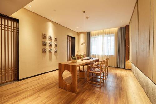 a dining room with a wooden table and chairs at 品缦芸酒店长沙高铁南站沙湾公园地铁站店 in Changsha