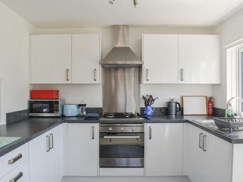 a kitchen with white cabinets and a stove top oven at 1 Merope in Padstow