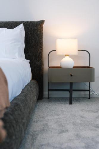 a bedroom with a bed and a table with a lamp at CASSA AURA PLACE - Modern 4BR Homes in Brisbane