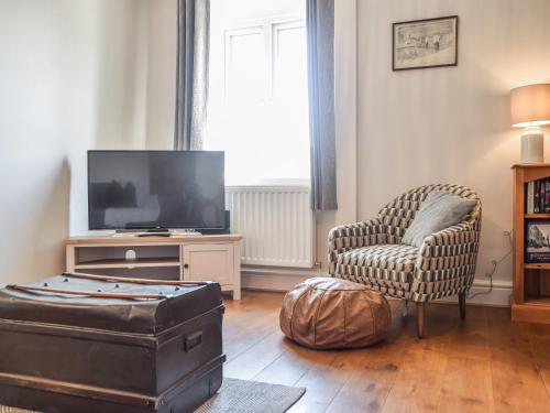 ein Wohnzimmer mit Fernseher und Sessel in der Unterkunft Rock Cottage in Bakewell