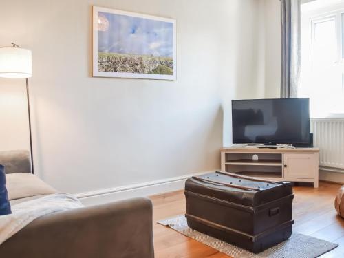 ein Wohnzimmer mit Fernseher und Koffer in der Unterkunft Rock Cottage in Bakewell