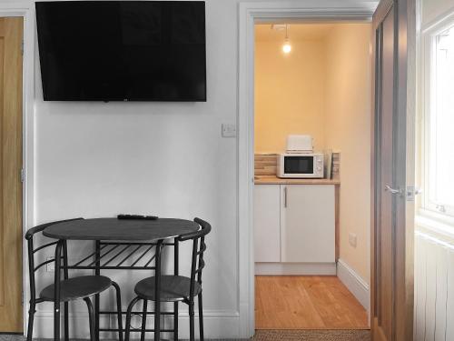 a small table with two chairs and a television on a wall at Denelea Studio 1 - Uk49952 in Scarborough