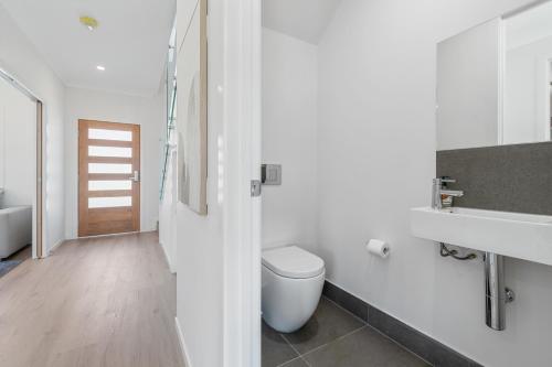 a white bathroom with a toilet and a sink at CASSA AURA PLACE - Modern 4BR Homes in Brisbane