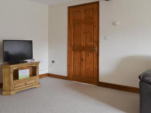 a living room with a tv and a wooden door at Church Farm Barn - Ukc3739 in Bawdeswell