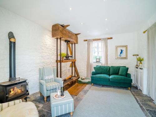a living room with a green couch and a stove at The Cider House in West Pennard