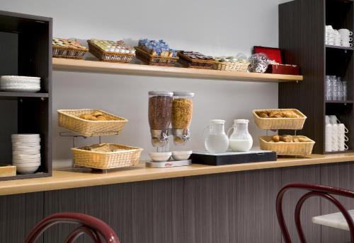 une étagère avec des bols et des paniers de nourriture dessus dans l'établissement Timhotel Boulogne Rives de Seine, à Boulogne-Billancourt