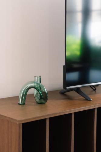 a green faucet on a wooden table next to a television at CASSA AURA PLACE - Modern 4BR Homes in Brisbane