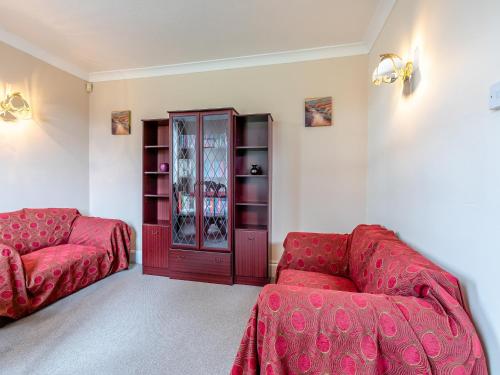 a living room with two red couches and a cabinet at Mulberry House in Highbridge