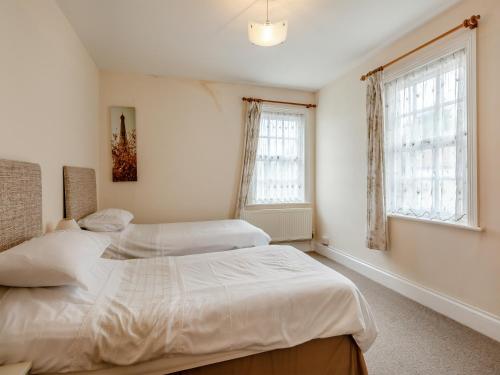 two beds in a bedroom with two windows at Mulberry House in Highbridge