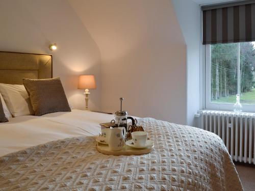 a bedroom with a bed with a tray with two tea sets on it at The Coach House in Alford