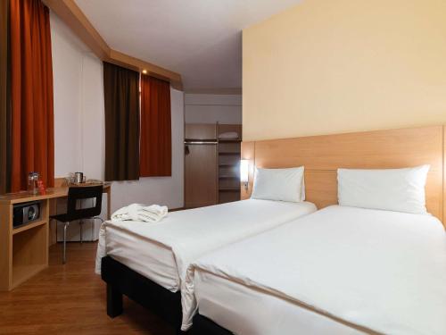 a hotel room with two beds and a desk at Ibis Astana in Astana