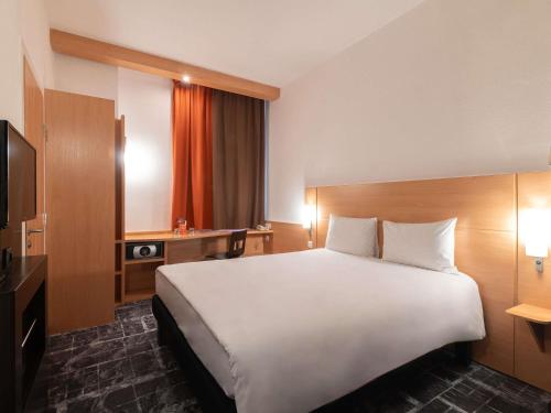 a hotel room with a large bed and a television at Ibis Astana in Astana
