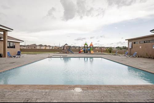 Una piscina con un parque infantil y dos personas al fondo. en Breezy Bungalow Gated 2BR w Pool WiFi, en Old Harbour