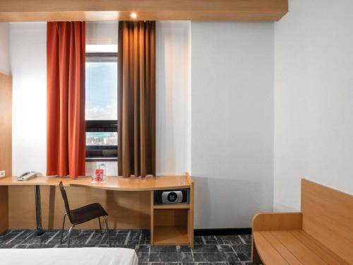 a hotel room with a desk and a window at Ibis Astana in Astana