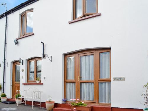 a white house with wooden windows at Draig's Cottage in Abergavenny