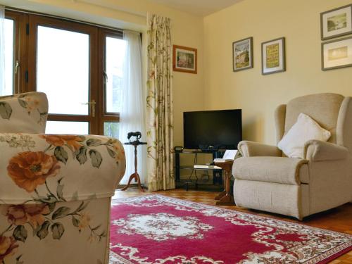 a living room with a couch and a chair and a television at Draig's Cottage in Abergavenny