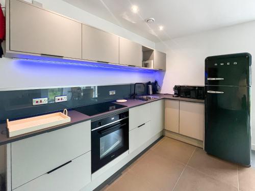a kitchen with white cabinets and a black refrigerator at Taigh Mullach Dearg in Portree