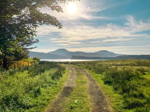 a dirt road through a field with mountains in the distance at Taigh Mullach Dearg in Portree