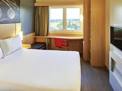 a room with a bed and a desk and a window at ibis Rio Branco in Rio Branco