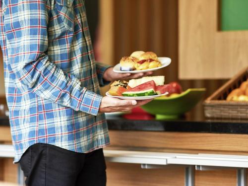 a man is holding two plates of food at ibis Rio Branco in Rio Branco