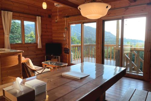 Una habitación de madera con una mesa y un balcón. en 海と田園風景を眺める高台に佇む景色抜群のログハウス #一棟貸切 #グループや家族旅行におすすめ #BBQ可のお庭 #夕陽と海が綺麗に見えるテラス #星空が綺麗 #南房総 #osora, en Minamiboso