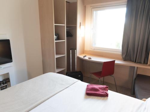 a room with a bed and a desk and a window at ibis Pilar in Pilar
