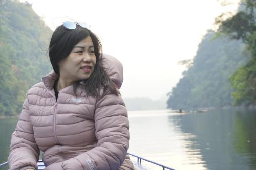 a woman sitting next to a body of water at Nhà nghỉ Quang Hưng in Ba Be