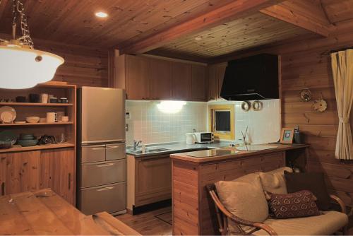 a kitchen with a refrigerator and a counter top at 南房総の海と田園風景を眺める高台に佇む景色抜群のログハウス #一棟貸切 #グループや家族旅行におすすめ #BBQ可のお庭 #夕陽と海が綺麗に見えるテラス #星空が綺麗 #南房総 #osora in Minamiboso