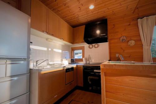 a kitchen with wooden cabinets and a stove top oven at 南房総の海と田園風景を眺める高台に佇む景色抜群のログハウス #一棟貸切 #グループや家族旅行におすすめ #BBQ可のお庭 #夕陽と海が綺麗に見えるテラス #星空が綺麗 #南房総 #osora in Minamiboso
