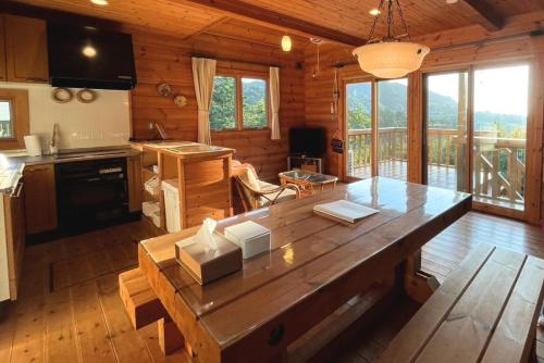 una cocina con una gran mesa de madera en una cabaña en 海と田園風景を眺める高台に佇む景色抜群のログハウス #一棟貸切 #グループや家族旅行におすすめ #BBQ可のお庭 #夕陽と海が綺麗に見えるテラス #星空が綺麗 #南房総 #osora, en Minamiboso