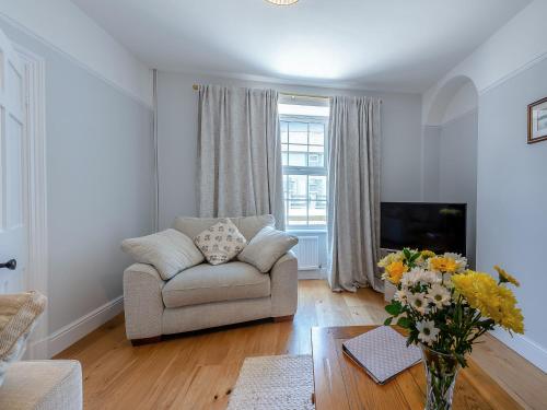 a living room with a couch and a vase of flowers at Spring Gardens in New Quay