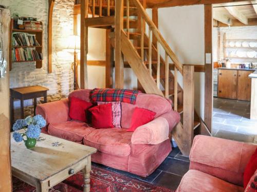 un soggiorno con divano rosso e scale di Thatched Cottage - Uk50261 a Llandeilo