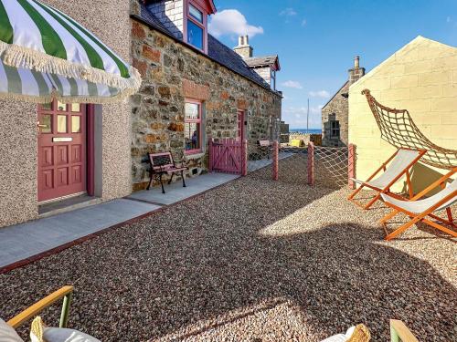 a patio with a rocking chair and a building at Coast Away in Fraserburgh