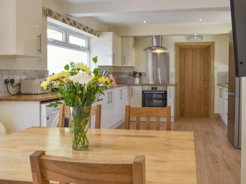 a vase of flowers on a wooden table in a kitchen at Brynllin Holiday Cottages - Dildre in Penuwch