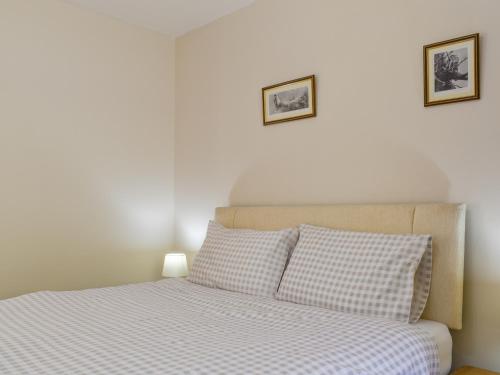a bedroom with a bed with two pictures on the wall at Brynllin Holiday Cottages - Dildre in Penuwch
