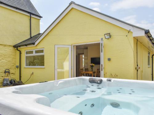 a bath tub in front of a yellow house at Brynllin Holiday Cottages - Dildre in Penuwch