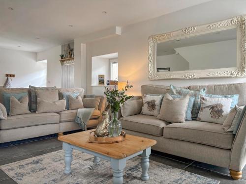 un salon avec des canapés et une table avec un miroir dans l'établissement Tosside Fold Cottage, à Tosside
