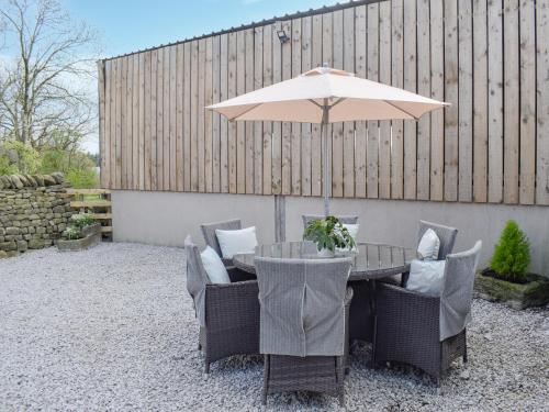 une table de patio avec un parasol et des chaises dans l'établissement Tosside Fold Cottage, à Tosside