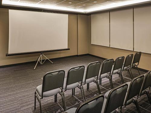 a conference room with chairs and a screen at ibis Jundiai Shopping in Jundiaí