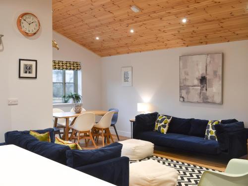a living room with a blue couch and a table at Hen Harrier Lodge-Uc3979 in Saint Columb Major