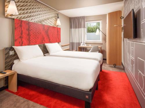 a hotel room with a large bed and a red carpet at ibis Lille Centre Grand Palais in Lille