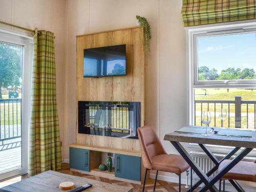 a living room with a table and a tv and two windows at Fairways Retreat 2 - Uk50247 in Cottingham