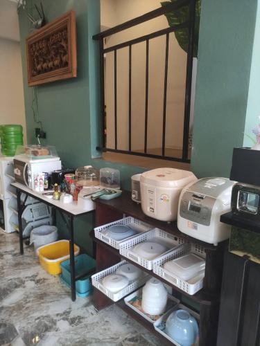 a kitchen with a shelf with dishes and appliances at อยู่สบายวิลล่า ยโสธร in Yasothon