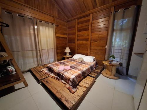 a bedroom with a bed in a wooden room at Cabana de madeira entre as árvores in Piedade