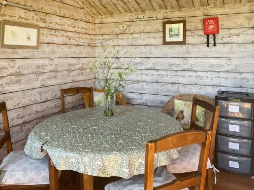 Una mesa de comedor con un jarrón de flores encima. en Brown Hare - Uk49799, en Brecon