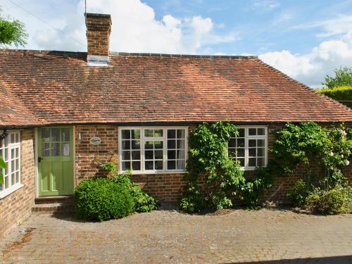 ein Backsteinhaus mit grüner Tür und Fenstern in der Unterkunft Cowbeech Farm Cottage in Herstmonceux