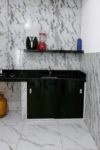 a kitchen with a black sink and white marble walls at Casa na segunda praia in Morro de São Paulo