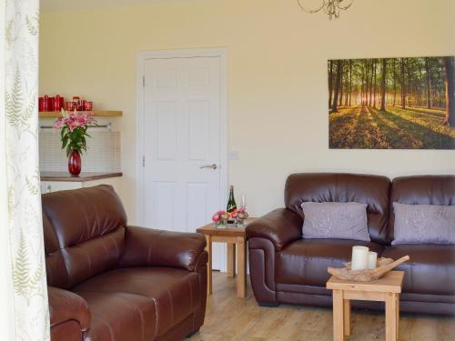 ein Wohnzimmer mit einer Ledercouch und einem Tisch in der Unterkunft Kestral Cottage in Shotton