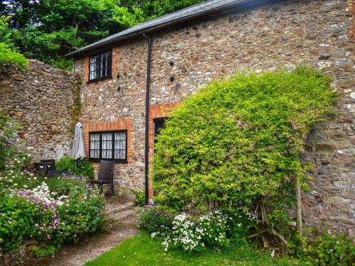 ein Steingebäude mit einer Bank im Garten in der Unterkunft Cider Cottage - Uk50076 in Sidmouth
