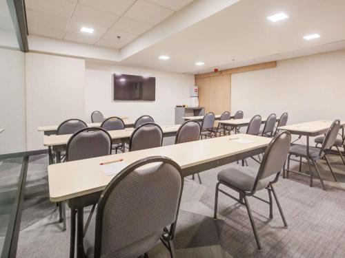 a conference room with tables and chairs and a screen at ibis Rio de Janeiro Nova America in Rio de Janeiro